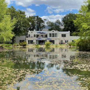 Klein Champagne Guesthouse and Cottages: a white house with a pond in front of it