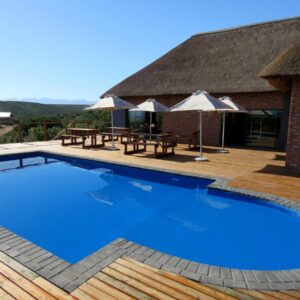 Klein Karoo Game Lodge: a large blue swimming pool next to a building