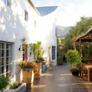Kogman & Keisie Guest Farm: a patio of a white building with tables and chairs