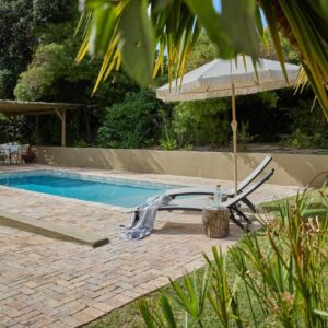 Kokon Boutique Guesthouse: a chair and an umbrella next to a swimming pool