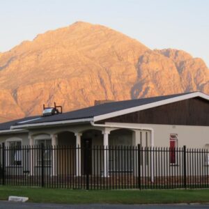 Koraalboom Guesthouse: a building with a fence in front of a mountain