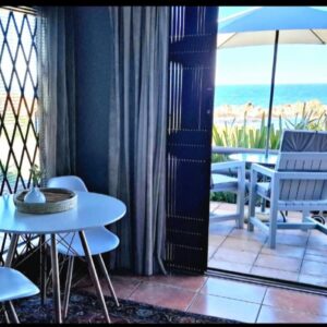 La Mer Seafront Selfcatering Accommodation Kleinmond: a balcony with a table and chairs and an umbrella