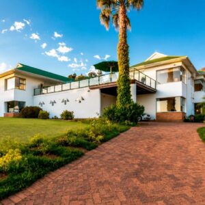 La Sandra Guest House: a house with a palm tree and a brick driveway