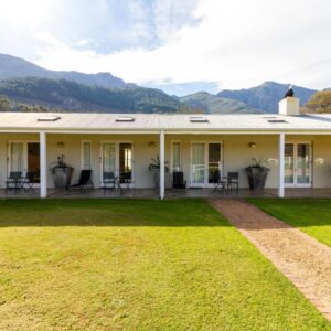 La Terra de Luc: a white house with a lawn and mountains in the background