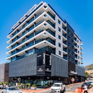 Latitude Aparthotel by Totalstay: a tall building with cars parked in a parking lot