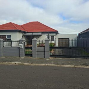 Le Cape Nest Guest House: a fence in front of a white house with a red roof