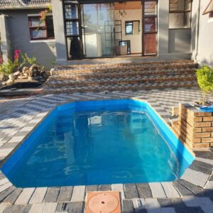 Ludiz Self Catering Guest House: a blue swimming pool in front of a house