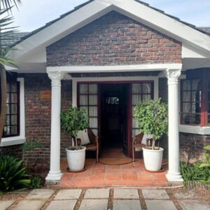 Marinda's B&B: a brick house with two potted plants on the front door