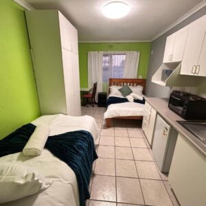 M&D Guest House: a room with two beds and a kitchen with green walls
