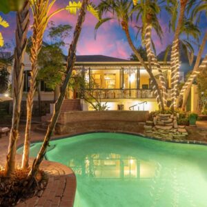 Mediterranean Villa Guesthouse: a swimming pool in front of a house with palm trees