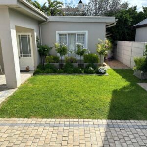 Melkbos Holiday Accommodation: a house with a yard with green grass