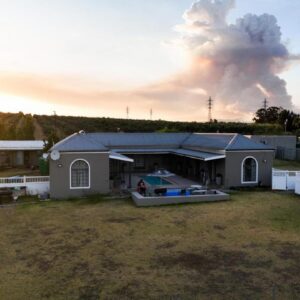 Mooi Uitsig Lodge: a house with a boat in a yard with a smoke stack