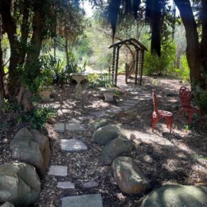 Mountain Hideaway, Hout Bay: a garden with rocks and chairs and a tree