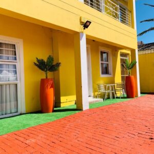 Mowetu Guest House: a yellow house with orange vases on the side of it