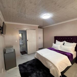 New Dawn Guest House: a bedroom with a large bed with a purple blanket