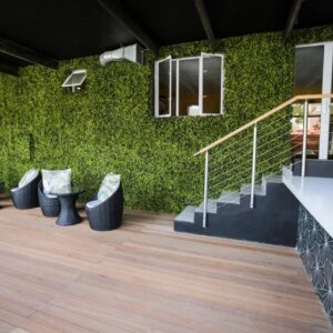 New National Hotel and Conference: a building with a green wall with a row of stools
