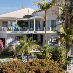 Ocean Watch Guest House: a large white house with a swimming pool and palm trees