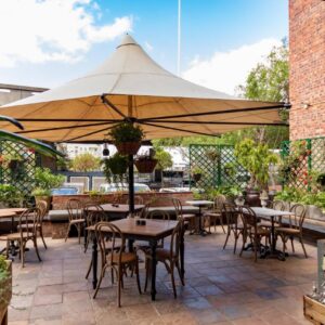 Old Foundry Hotel by Ideas Cartel: a patio with tables and chairs and an umbrella
