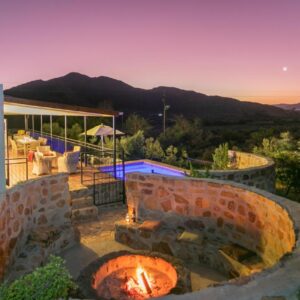 Olive Hill Guest House: a patio with a brick fire pit in front of a house