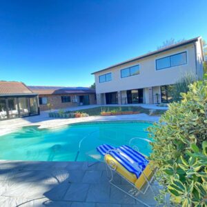 On Point Tranquil Garden Constantiaberg: a swimming pool with two lounge chairs in front of a house