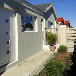 Our Nest Guest House: a white house with a door and a fence