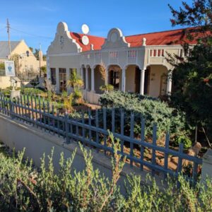 Ouwerf Guesthouse: a house with a fence in front of it