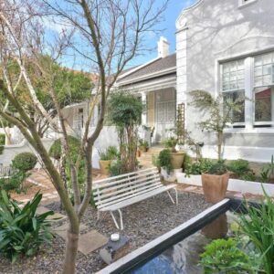 Parker Cottage Guesthouse: a white house with a bench in the yard