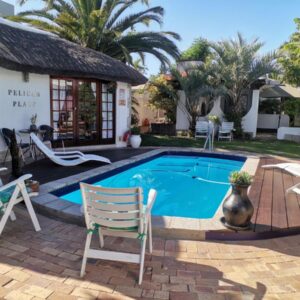 Pelican Place Guest Cottages: a swimming pool with chairs and a house