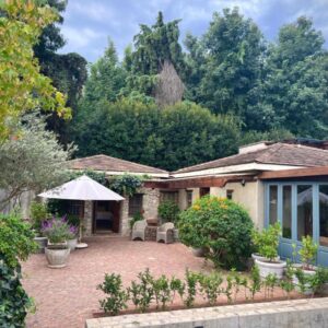 Penny Royal Guest Cottages: a house with a patio with chairs and trees