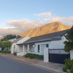 Petit Ermitage: a white house on a street with mountains in the background
