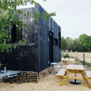 Piketburg Farm Tiny Home - PodInn: a black building with a picnic table in front of it