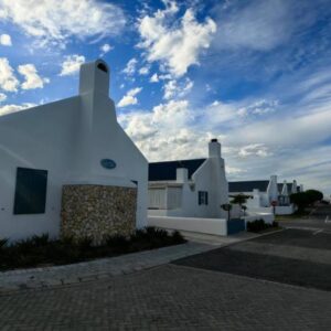 Pilgrim's Inn - Paternoster: a white house with a blue sky with clouds