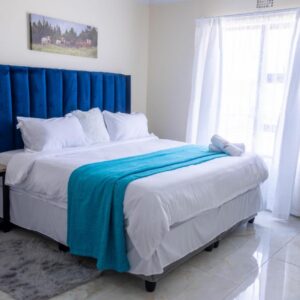 Premier Guest House: a bedroom with a large bed with a blue headboard