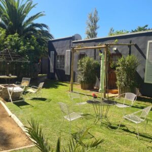 Prosper Stud Guest House: a yard with chairs and a table and a house