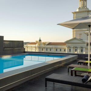 Protea Hotel by Marriott Cape Town North Wharf: a swimming pool with umbrellas and benches next to a building