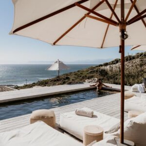 Pure Sea Boutique Lodge: a pool with white chairs and an umbrella and the ocean