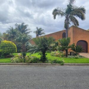 Red Door Strand Guest house: a brick building with palm trees in front of it