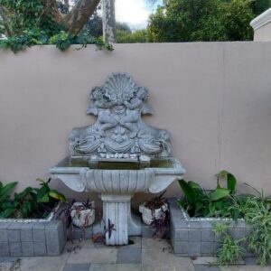 Roosboom Guest Apartments: a stone fountain in front of a wall with plants