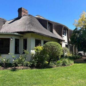 Shire Lodge: an old house with a thatched roof and a yard