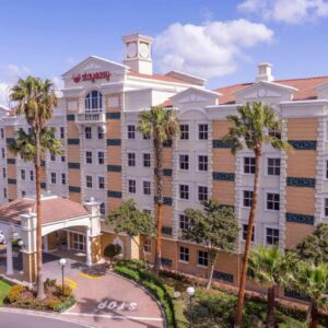 StayEasy Century City: a large building with palm trees in front of it
