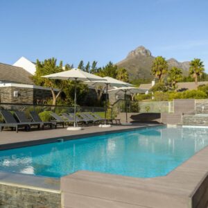 Stellenbosch Luxury Apartments: a pool with chairs and umbrellas next to a house