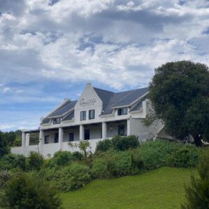 Stilbaai River Lodge: a large white house on top of a green field