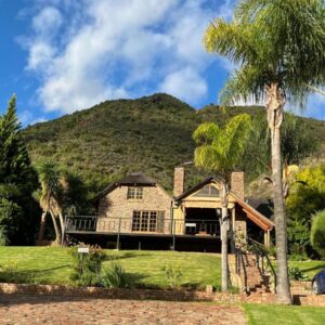 Stonebreaker Country Lodge: a house with palm trees in front of a mountain