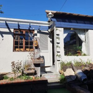 Strand Guesthouse: a small white house with a blue awning