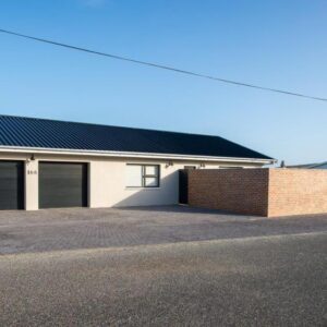 Struisbaai Apartments: a white building with two garage doors and a brick wall