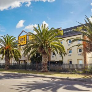 SUN1 Parow Cape Town: a hotel with palm trees in front of a fence