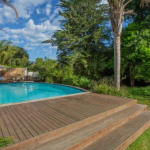 Tehillah Guest House: a swimming pool with a wooden deck next to a house