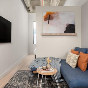 The Acre by Neighbourgood: a living room with a blue couch and a tv