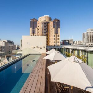 The Barracks Apartments: a balcony with umbrellas and a swimming pool on a building