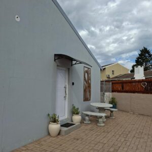 The Lazy Lodge: a white building with a patio with a bench